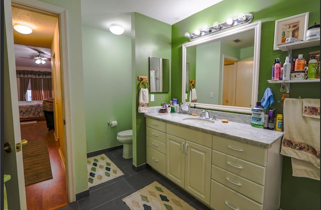 bathroom with ceiling fan, tile patterned flooring, a textured ceiling, toilet, and vanity