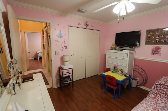 bedroom featuring ceiling fan, dark hardwood / wood-style flooring, crown molding, and a closet