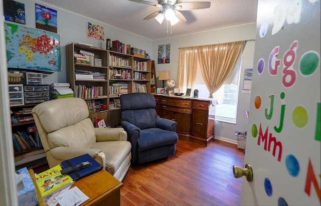 sitting room with hardwood / wood-style floors, a textured ceiling, ceiling fan, and ornamental molding