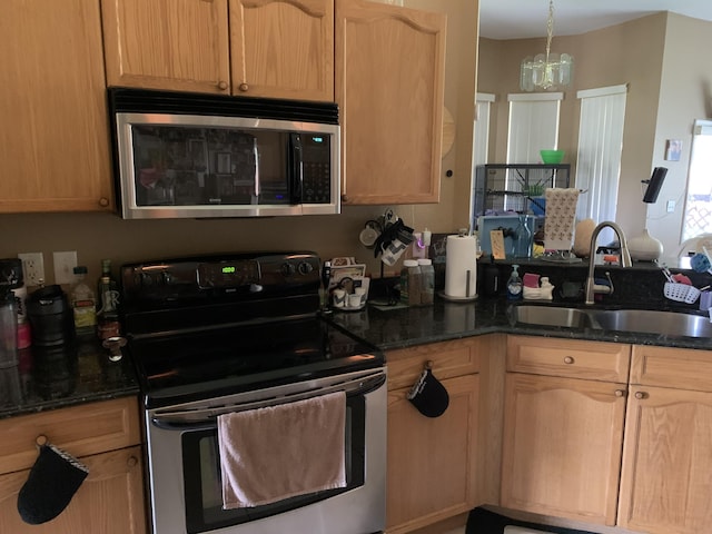 kitchen with light brown cabinetry, stainless steel appliances, sink, a notable chandelier, and dark stone countertops