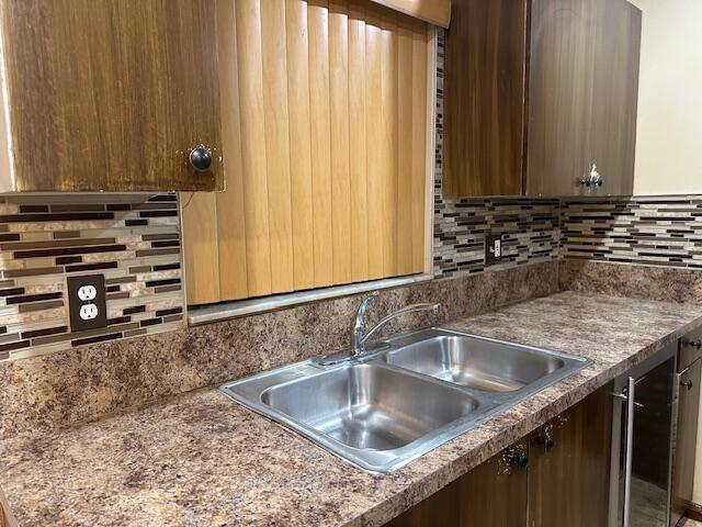 kitchen featuring tasteful backsplash, dark countertops, and a sink