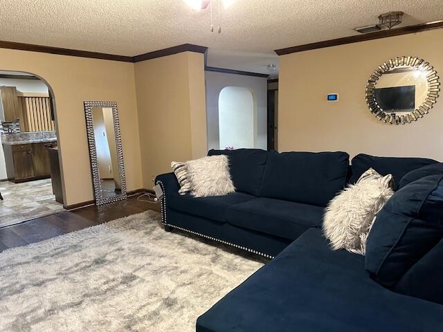 living room featuring dark hardwood / wood-style flooring, crown molding, and a textured ceiling