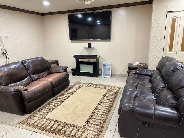 tiled living room with crown molding and a fireplace