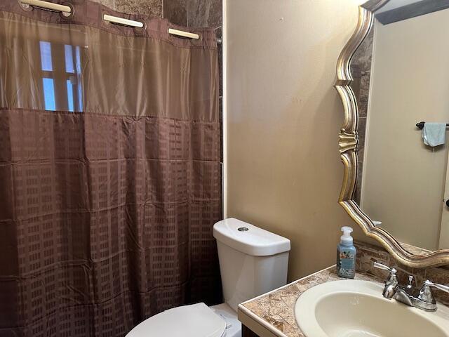 full bathroom with toilet, curtained shower, and vanity