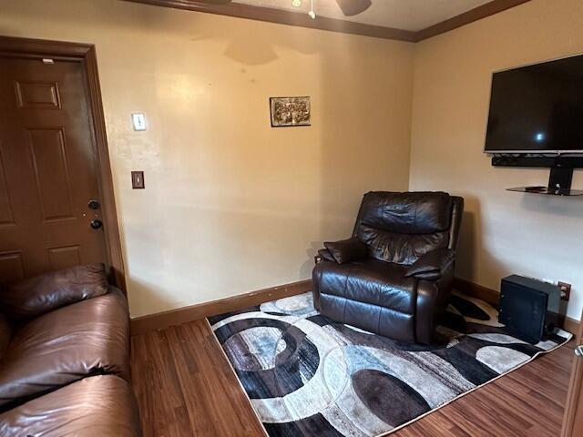 living area with ornamental molding, baseboards, and wood finished floors