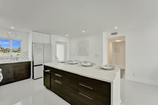 kitchen with white cabinets, sink, a kitchen island, light tile patterned floors, and white fridge