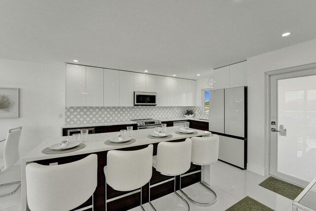 kitchen featuring backsplash, white cabinetry, a breakfast bar area, and appliances with stainless steel finishes