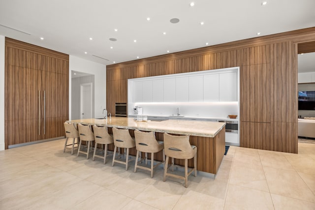 kitchen with white cabinetry, sink, a breakfast bar area, and a large island with sink