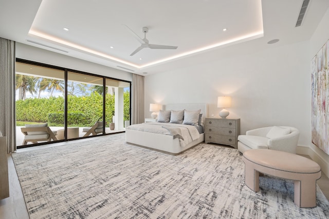 bedroom featuring a tray ceiling, access to outside, and ceiling fan