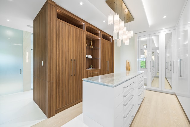 walk in closet with a notable chandelier and light wood-type flooring