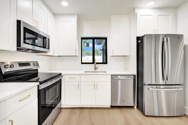 kitchen featuring appliances with stainless steel finishes, light hardwood / wood-style flooring, white cabinetry, and sink