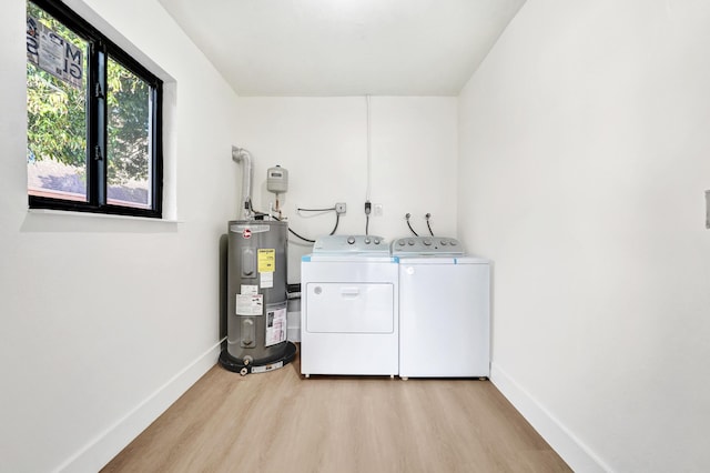 washroom featuring water heater, light hardwood / wood-style flooring, and washer and dryer