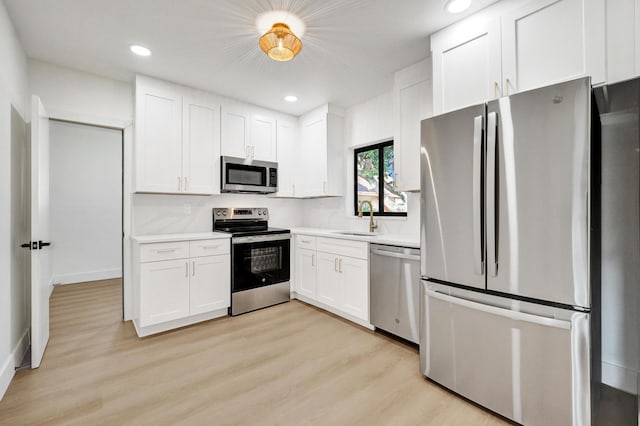 kitchen with white cabinetry, sink, stainless steel appliances, and light wood-type flooring