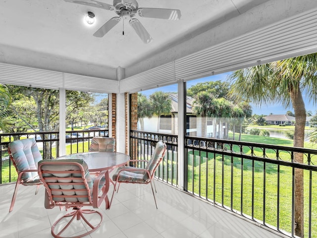 sunroom featuring ceiling fan and a water view