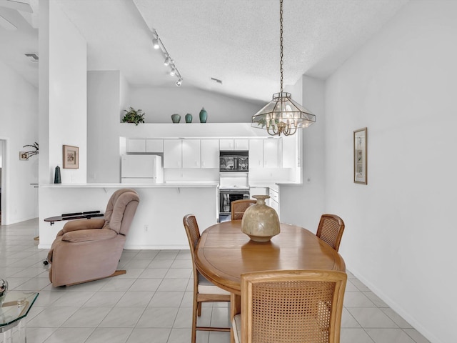 dining space with lofted ceiling, track lighting, a textured ceiling, light tile patterned flooring, and a chandelier