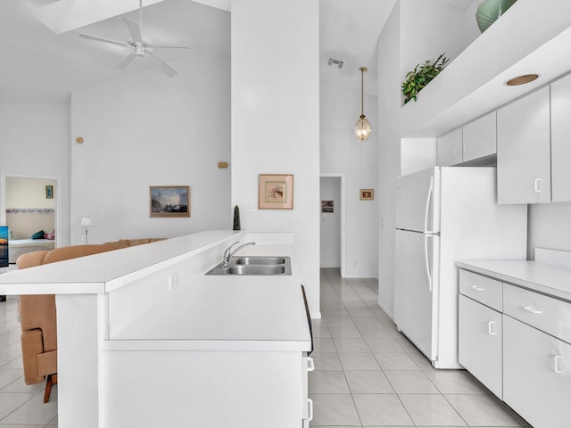 kitchen with sink, light tile patterned floors, kitchen peninsula, decorative light fixtures, and white cabinets