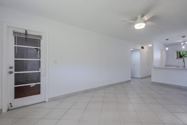 empty room with ceiling fan and light tile patterned floors