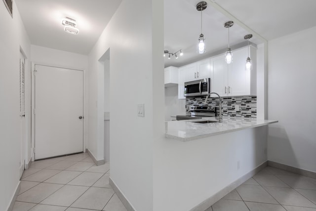 kitchen with backsplash, white cabinets, hanging light fixtures, appliances with stainless steel finishes, and kitchen peninsula