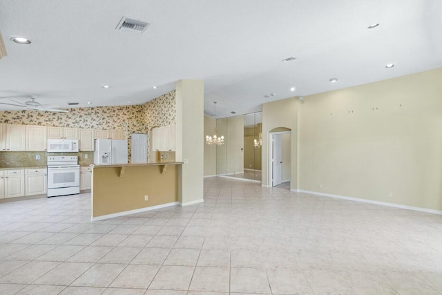 kitchen featuring a kitchen breakfast bar, white appliances, ceiling fan, and light tile patterned flooring