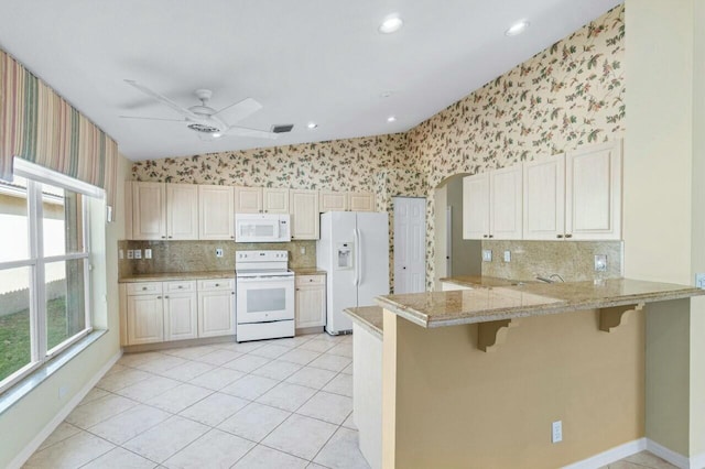 kitchen featuring white appliances, ceiling fan, light tile patterned floors, a kitchen bar, and kitchen peninsula