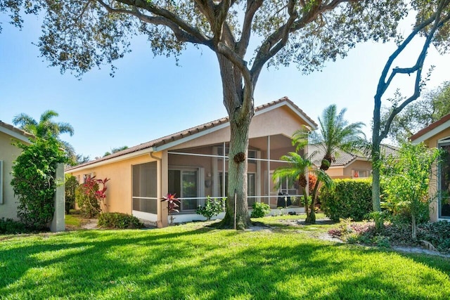 back of house featuring a sunroom and a lawn