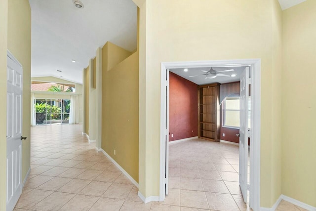 hallway with light tile patterned flooring and lofted ceiling