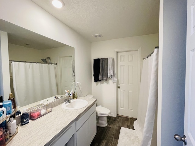 bathroom featuring hardwood / wood-style flooring, vanity, a textured ceiling, and toilet