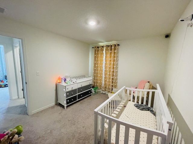 bedroom featuring light carpet and a nursery area