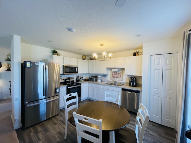 kitchen featuring stainless steel appliances, dark wood-type flooring, sink, decorative light fixtures, and white cabinets