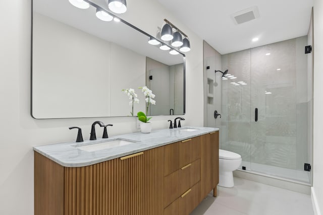 bathroom featuring a shower with door, vanity, and toilet