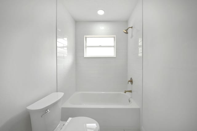 bathroom with tiled shower / bath, a textured ceiling, and toilet