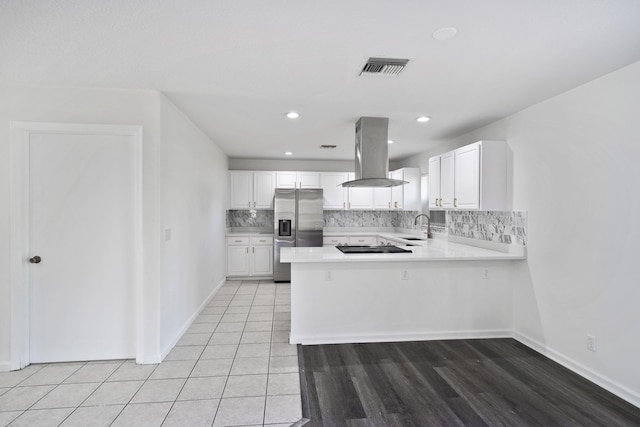 kitchen with sink, island exhaust hood, stainless steel fridge, kitchen peninsula, and white cabinets