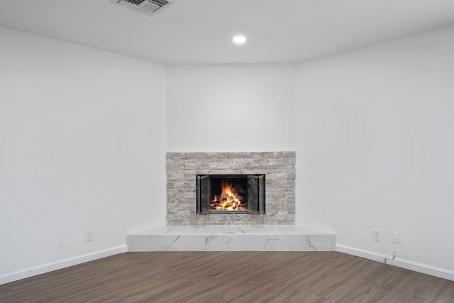 interior details with wood-type flooring and a stone fireplace