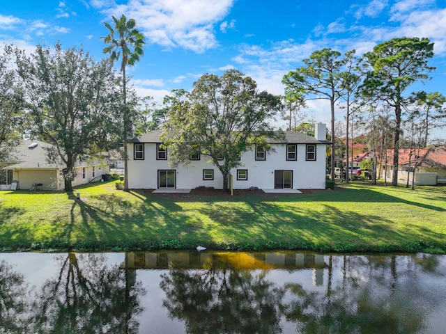 rear view of property featuring a water view and a yard