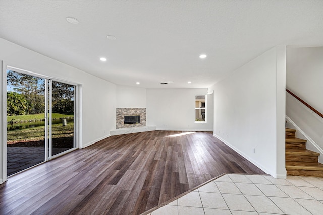 unfurnished living room with a stone fireplace and light hardwood / wood-style floors