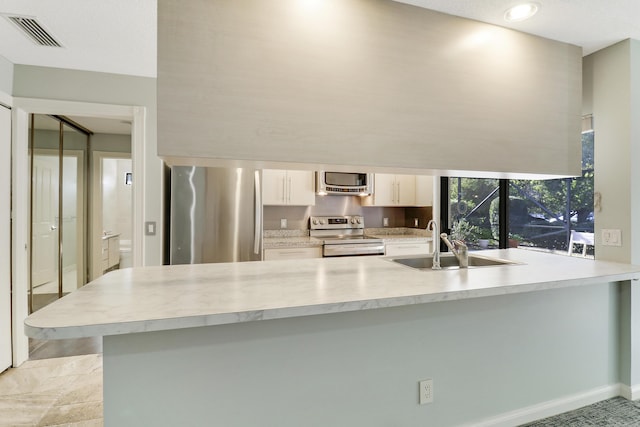 kitchen featuring kitchen peninsula, sink, white cabinetry, and stainless steel appliances