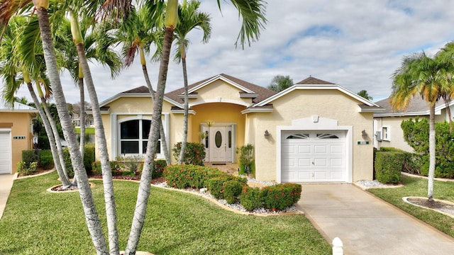 view of front of property featuring a front lawn, concrete driveway, an attached garage, and stucco siding