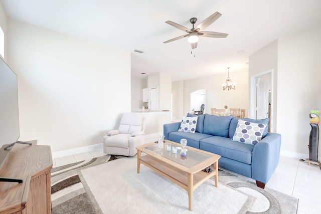 living area featuring light tile patterned floors, ceiling fan with notable chandelier, visible vents, and baseboards