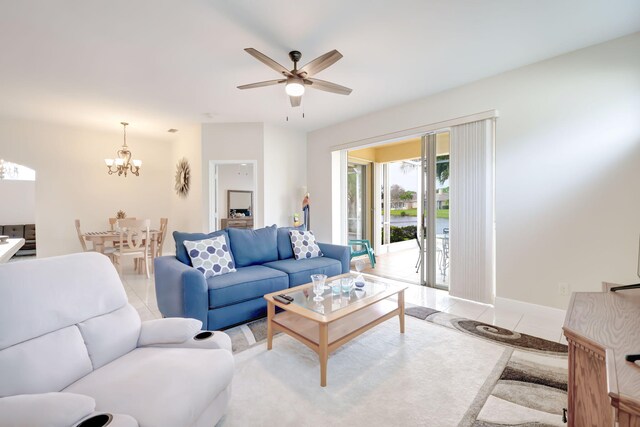 tiled living room with ceiling fan with notable chandelier