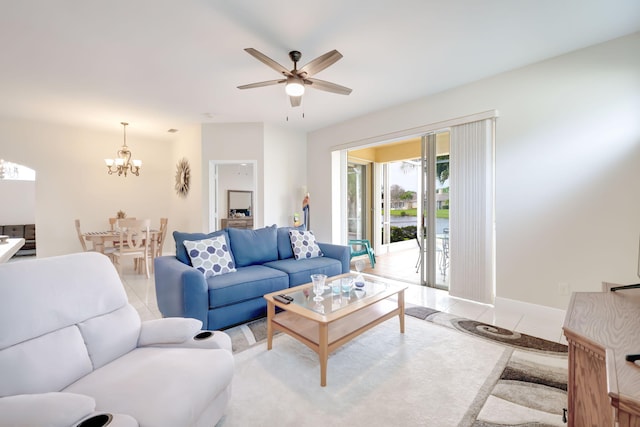 living area featuring ceiling fan with notable chandelier, baseboards, and light tile patterned floors