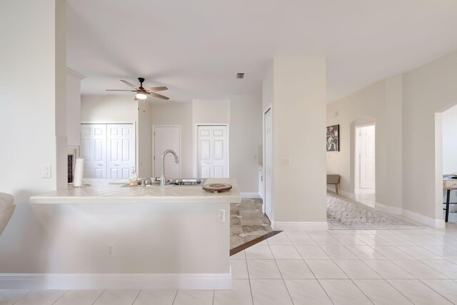 living room with light tile patterned flooring and ceiling fan with notable chandelier