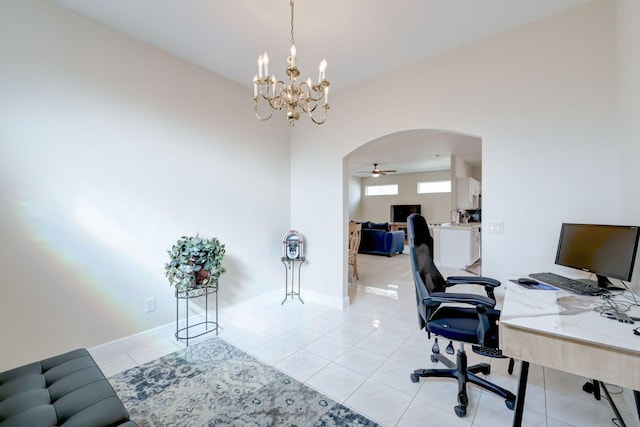 office space with a ceiling fan, arched walkways, baseboards, and light tile patterned floors