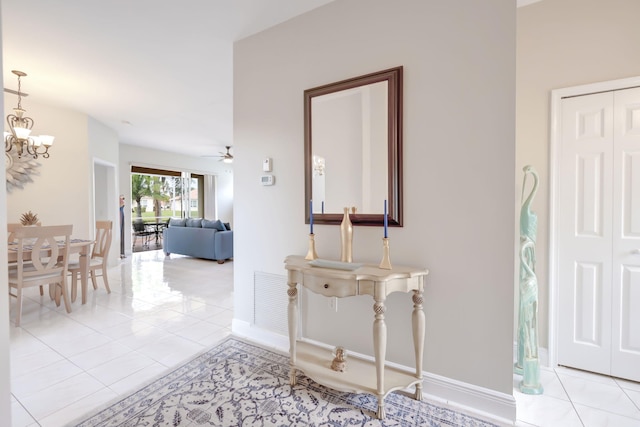 hall featuring light tile patterned flooring and a chandelier