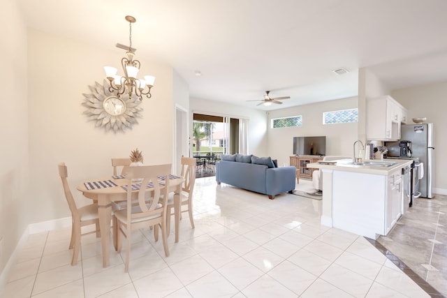 dining space with light tile patterned flooring, sink, and ceiling fan with notable chandelier