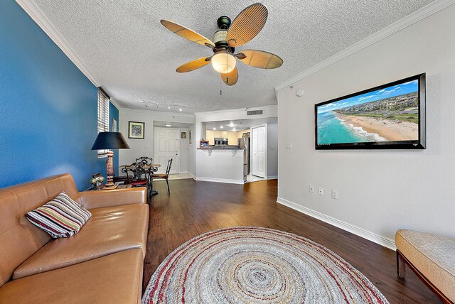 living room with a textured ceiling, ceiling fan, ornamental molding, and dark wood-type flooring