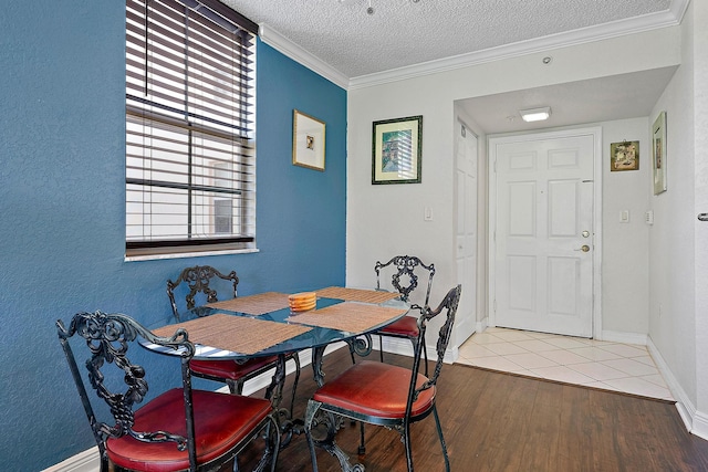 dining room featuring crown molding, light hardwood / wood-style flooring, and a textured ceiling