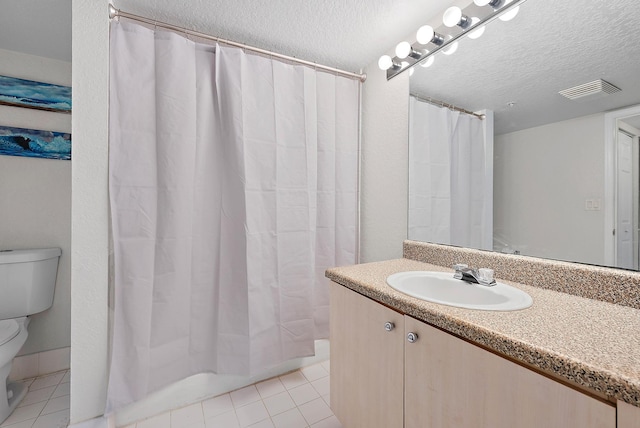 bathroom with tile patterned flooring, vanity, a textured ceiling, and toilet