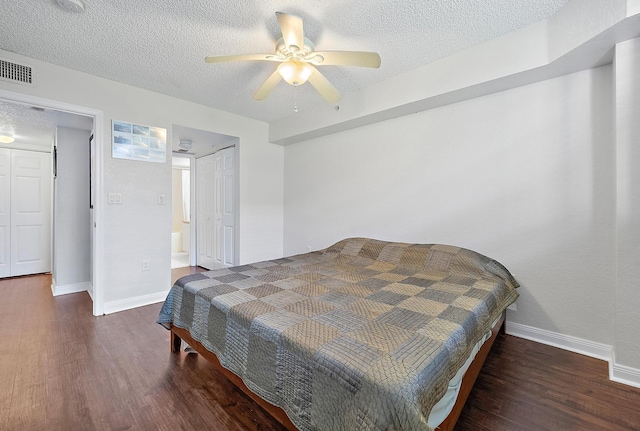 bedroom with a textured ceiling, ceiling fan, and dark wood-type flooring