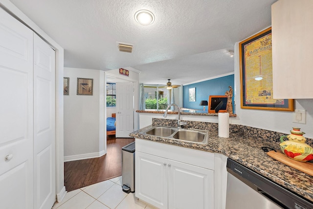 kitchen with white cabinets, a textured ceiling, sink, light tile patterned floors, and dishwasher