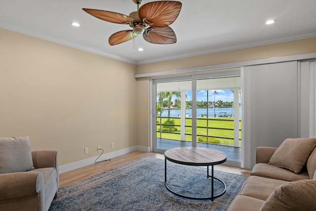 living room featuring crown molding, light hardwood / wood-style flooring, a water view, and ceiling fan